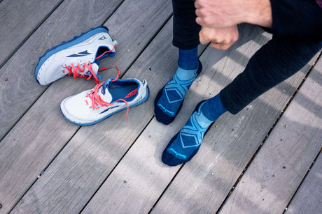 Someone wearing Smartwool socks getting ready to put on running shoes