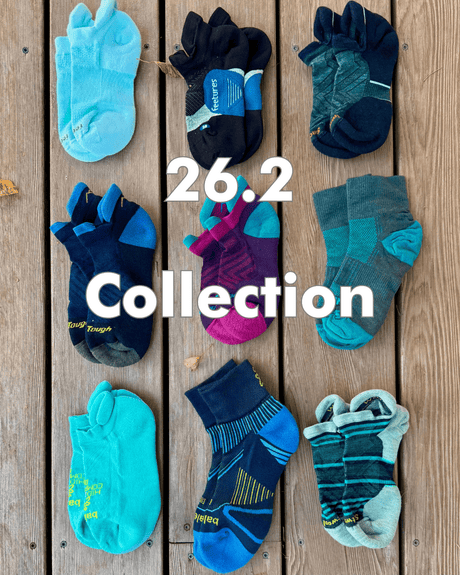 Collection of colorful socks on a wooden surface with '26.2 Collection' text.